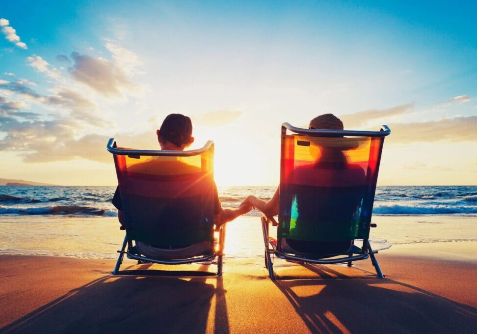 Two people sitting in lawn chairs on the beach